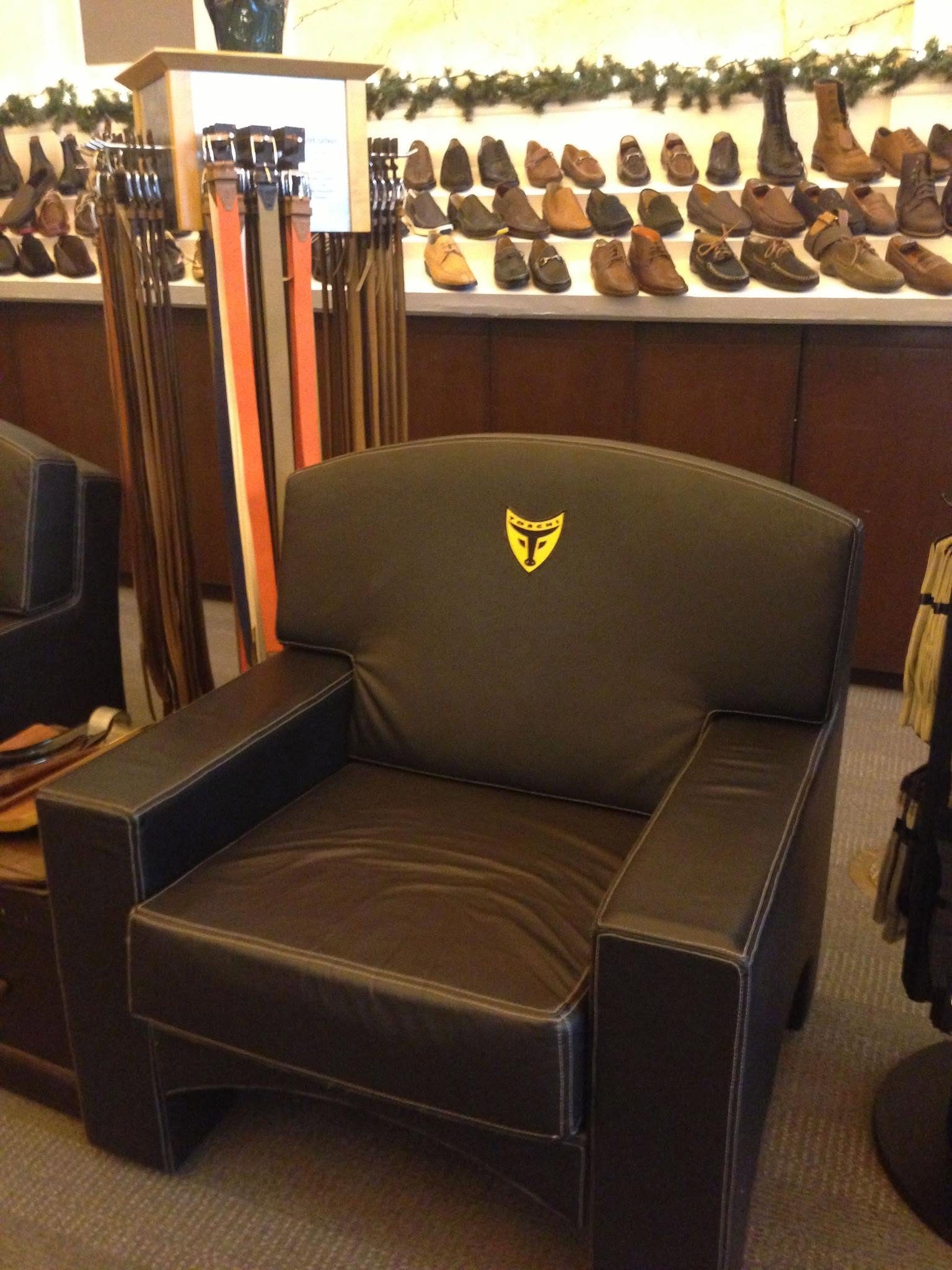 Leather armchair with the Toschi crest in front of a wall of shoes